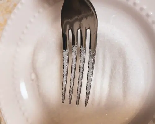 fork in white sugar on white plate