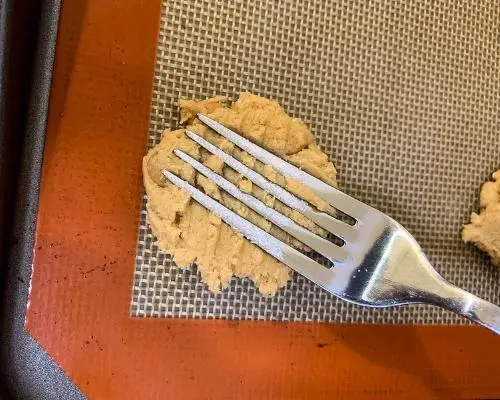 fork pushed into cookie dough on baking sheet